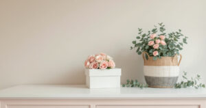 Boîtes à chapeau carrées garnies de roses roses et corbeille en osier à anses avec une plante fleurie