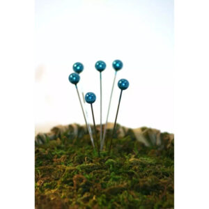 Épingles à tête perle nacrée bleu turquoise piquées dans de la mousse pour décoration florale de fleuriste